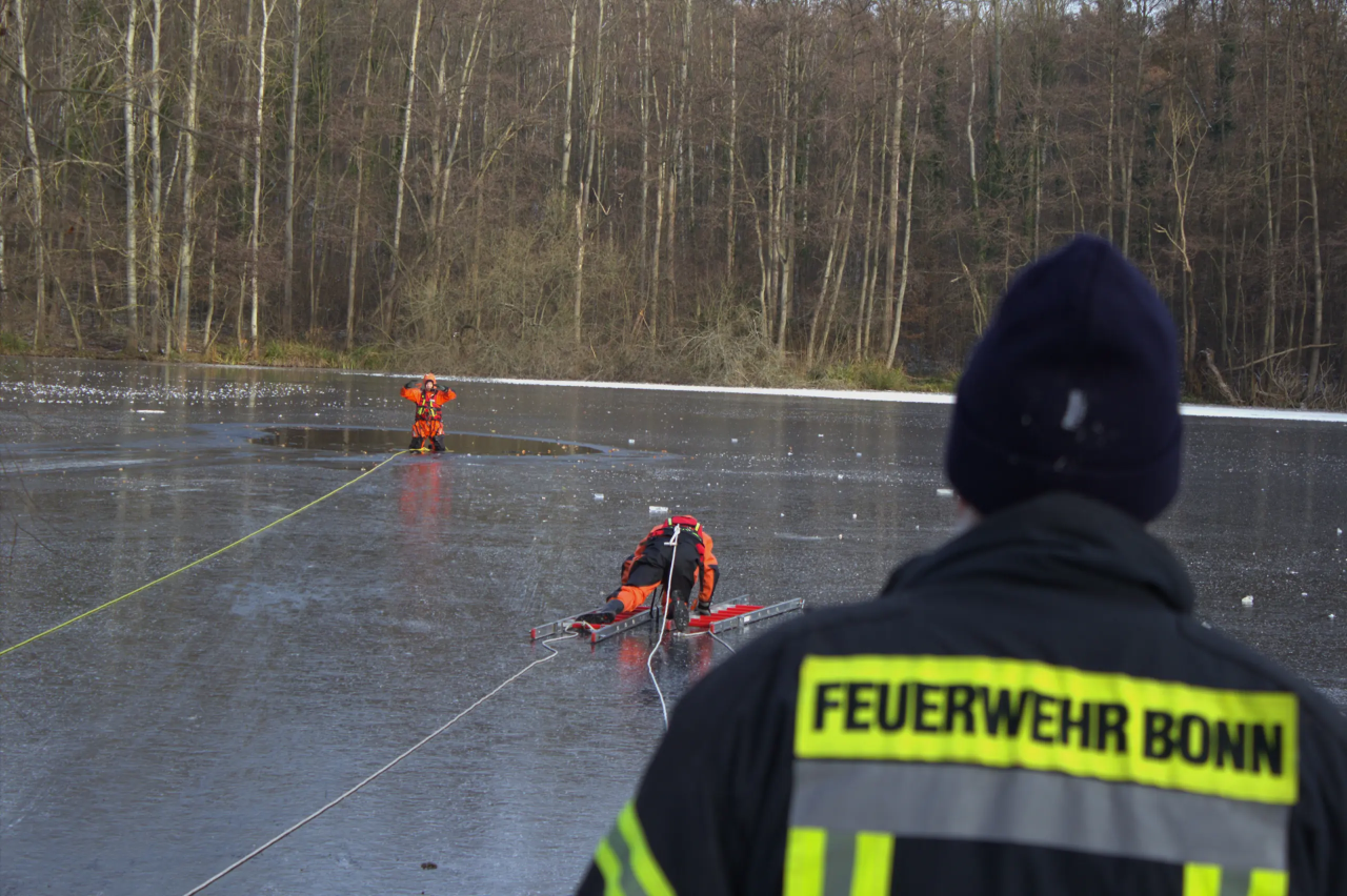 Ein Feuerwehrmann rettet jemanden aus einem zugefrorenen See.