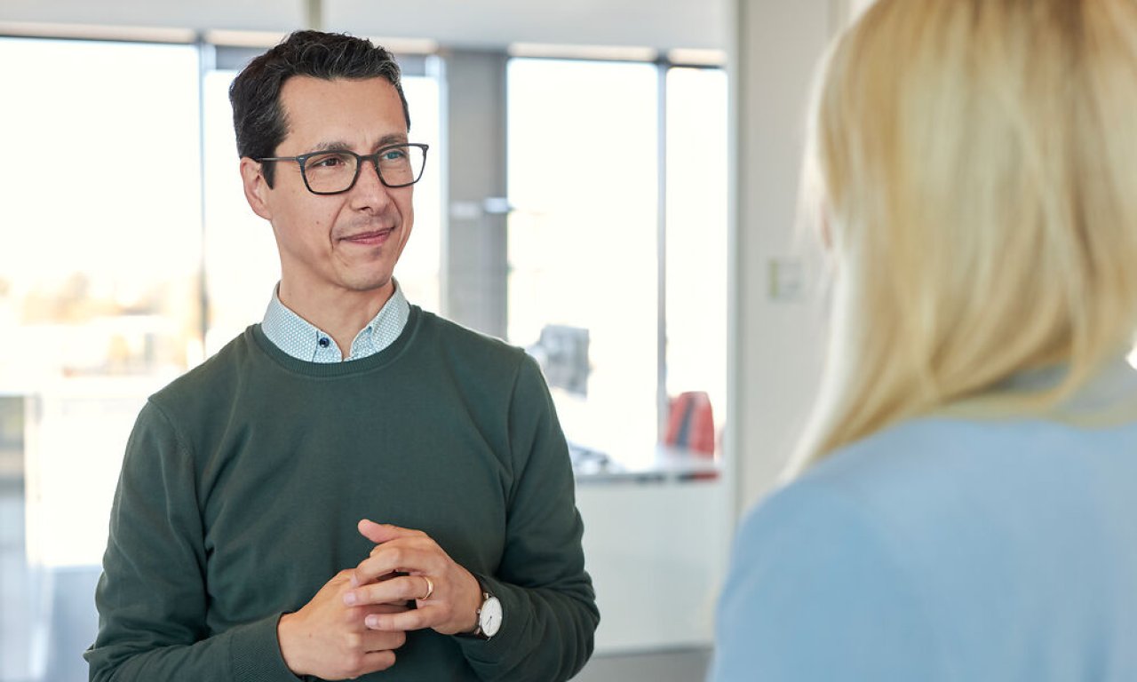 Ein dunkelhaariger Mann mit Brille im Gespräch mit einer blonden Frau.