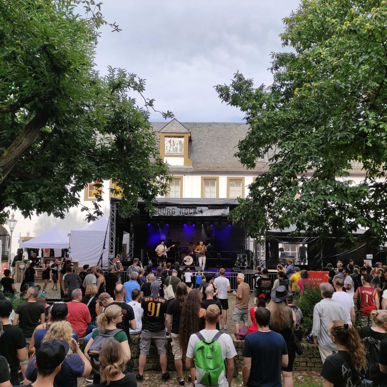 Eine Bühne mit Musikern vor der ein Publikum steht.