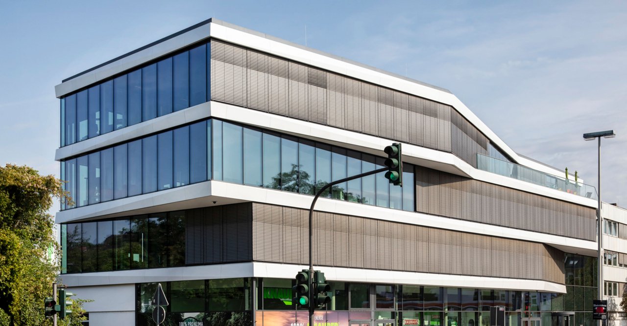Seitliche Ansicht eines modernen Bürogebäudes mit großen Fensterfronten.