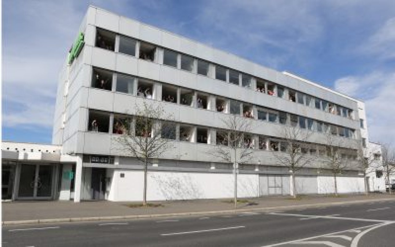 Mehrstöckiges Bürogebäude mit weißen Fassaden und mehreren Fenstern an einer Straßenkreuzung.