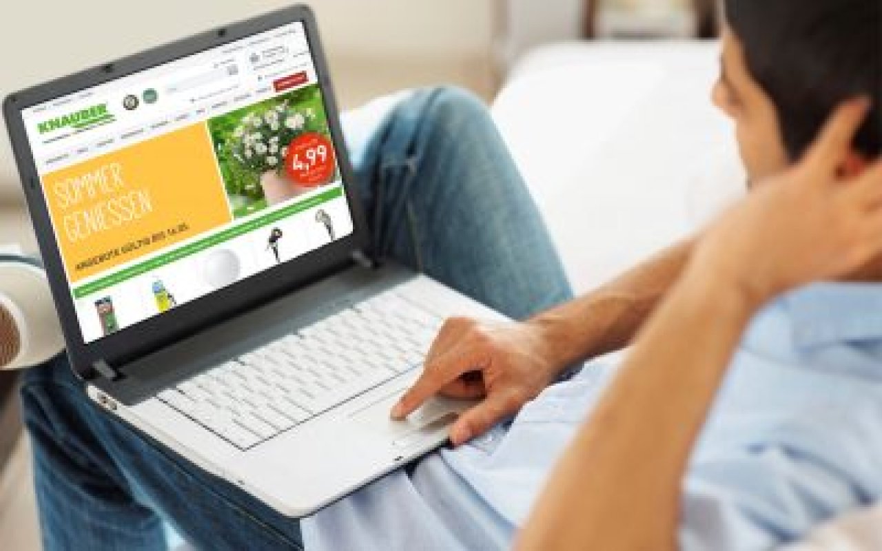 Person sitzt mit Laptop auf dem Schoß und besucht die Webseite von Knauber mit Angeboten für Sommergenuss.
