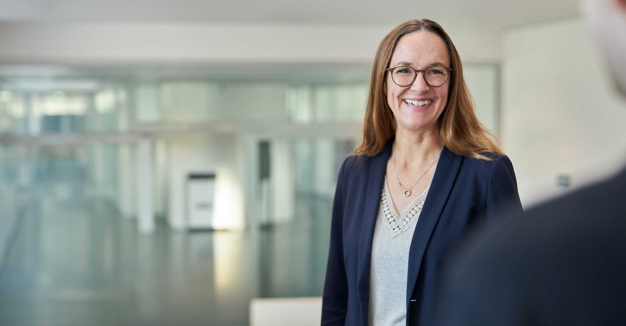 Frau mit Brille lacht in die Kamera.