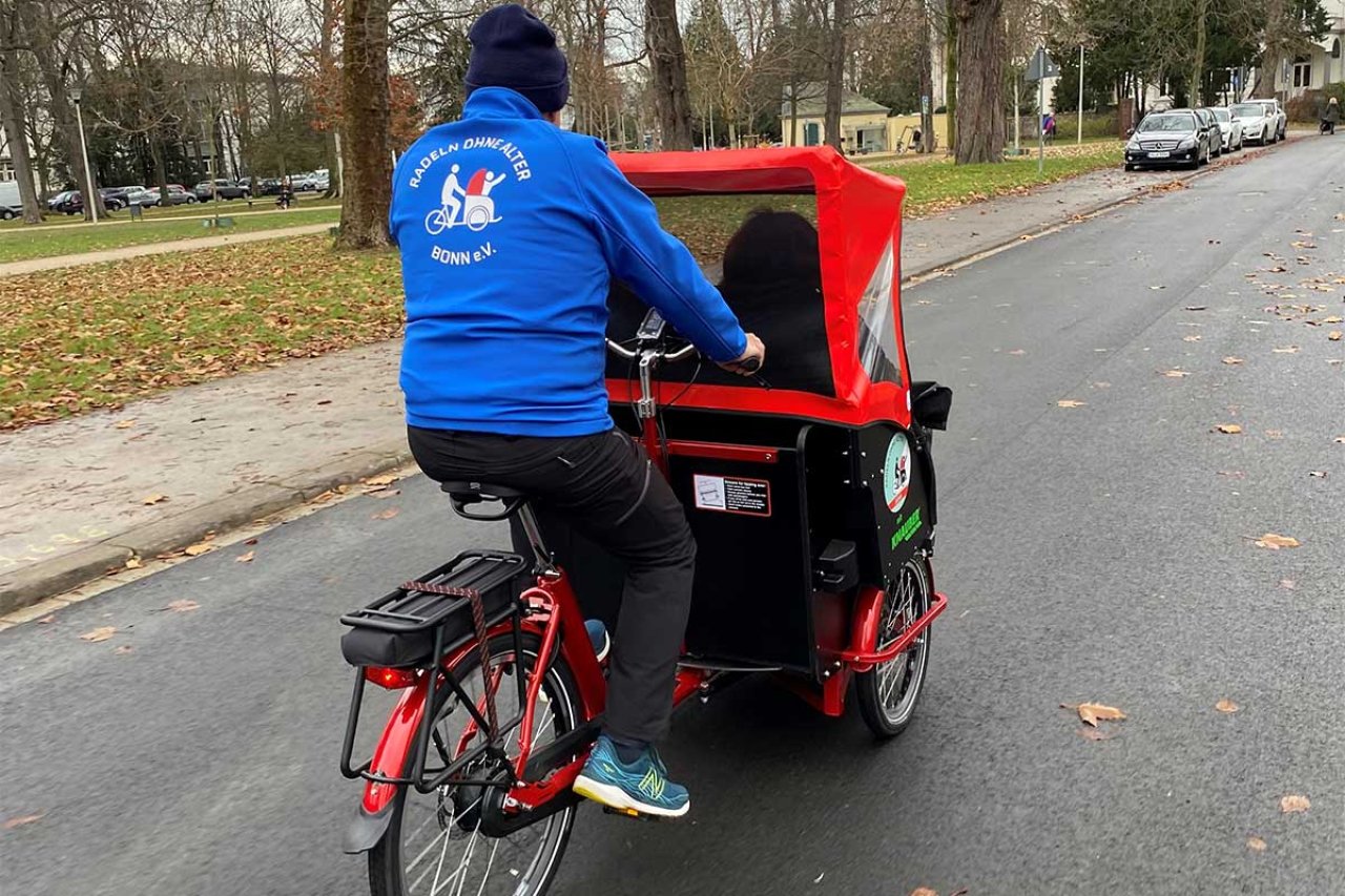 Person mit blauer Jacke auf einem Lastenfahrrad.