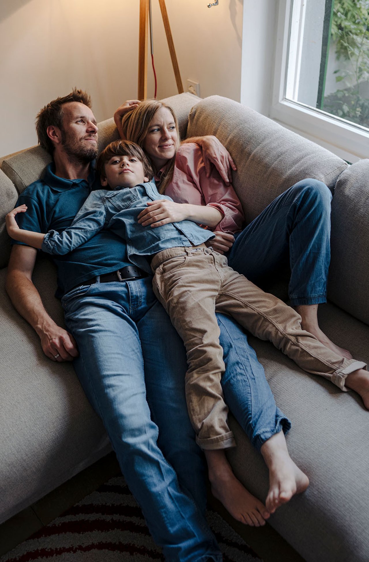 Eine Familie liegt auf einem grauen Sofa.