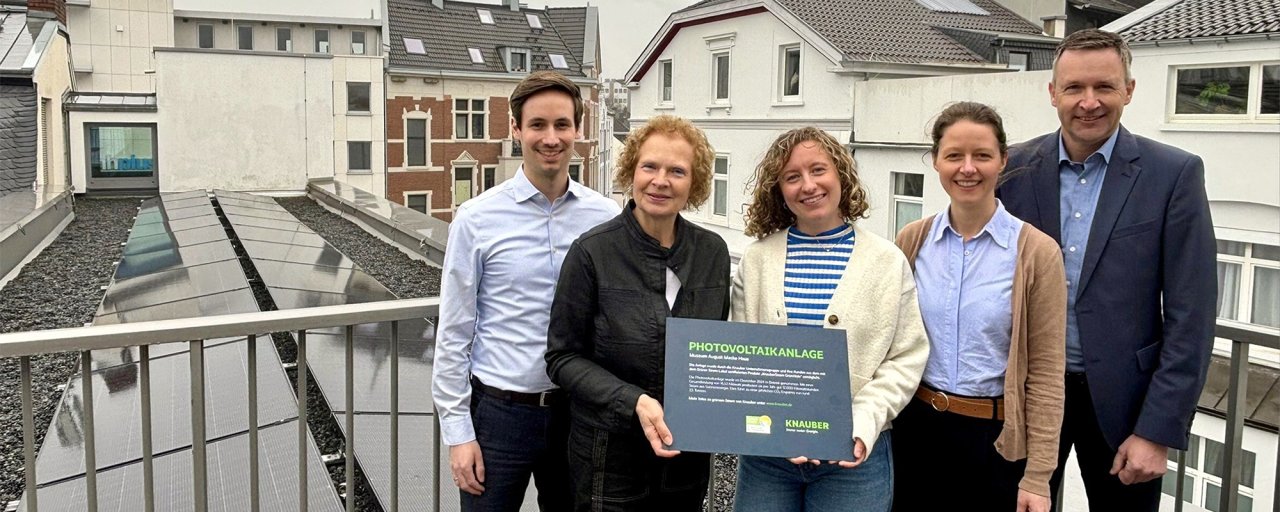 Gruppenbild mit 5 Personen halten Schild vor neuer PV-Anlage.
